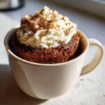 A delicious Pumpkin Spice Latte Mug Cake topped with whipped cream and a sprinkle of cinnamon.