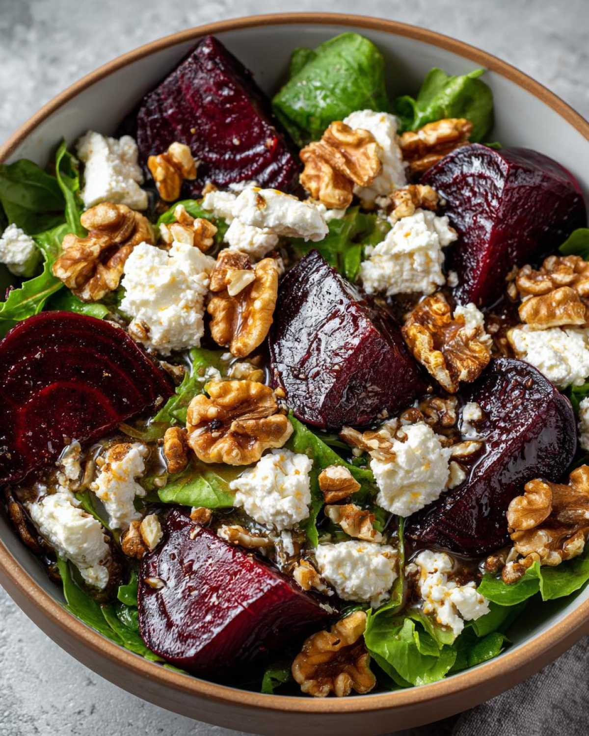 Close-up of a vibrant Roasted Beet & Goat Cheese Salad with fresh greens, crumbled goat cheese, and toasted walnuts.