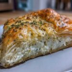 A delicious slice of Rosemary Goat Cheese Tart with flaky pastry and creamy goat cheese filling, sprinkled with fresh rosemary.