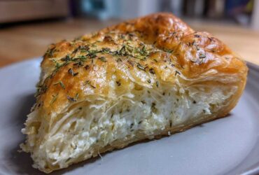 A delicious slice of Rosemary Goat Cheese Tart with flaky pastry and creamy goat cheese filling, sprinkled with fresh rosemary.
