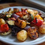 A white plate filled with colorful roasted vegetables and gnocchi, showcasing a delicious Sheet Pan Gnocchi & Vegetables meal.