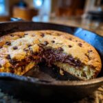 A warm Skillet Chocolate Chip Cookie with a gooey, melted chocolate center, baked in a cast iron skillet.