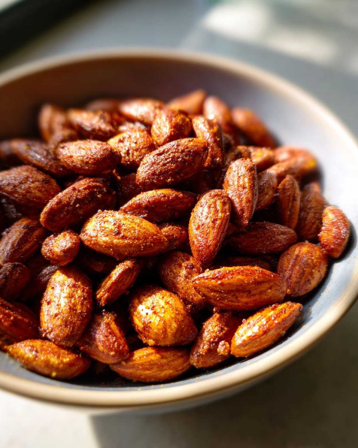 A close-up of a bowl filled with delicious Smoky Paprika Almonds, seasoned with spices.