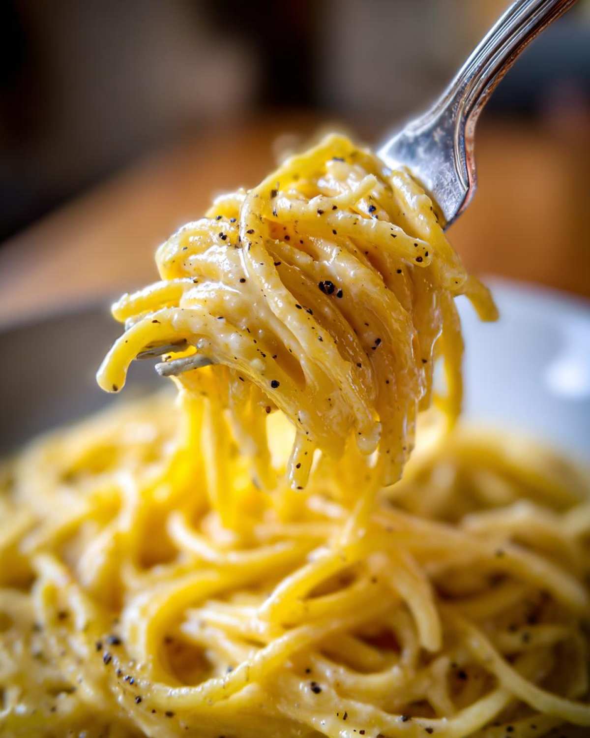 A fork twirls creamy Spaghetti Cacio e Pepe, coated in cheese and black pepper.