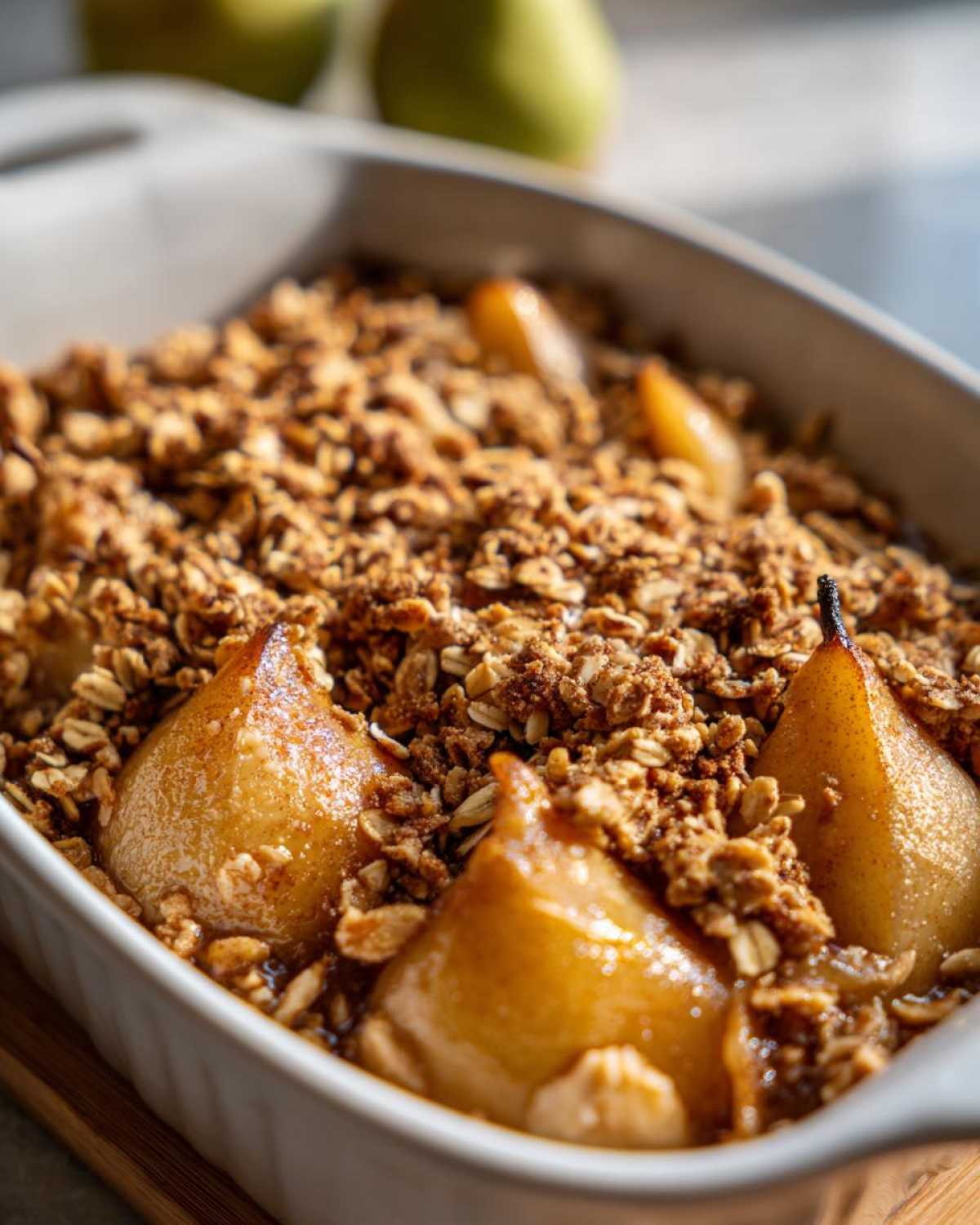 A close-up view of a Spiced Pear Crisp baked in a white dish, featuring tender pears and a golden oat topping.