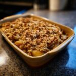 A golden-brown Spiced Pear Crisp baked in a ceramic dish, with a crunchy oat topping.