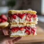 Two stacked Strawberry Shortcake Ice Cream Sandwiches, showing layers of biscuit, cream, and fresh strawberries.