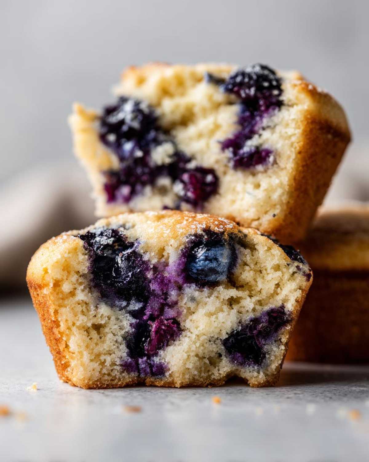 Close-up of a vegan blueberry muffin, cut in half, revealing juicy blueberries and a fluffy interior.
