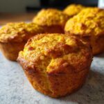 Close-up of golden-brown vegan protein muffins, showcasing their fluffy texture and slightly cracked tops.
