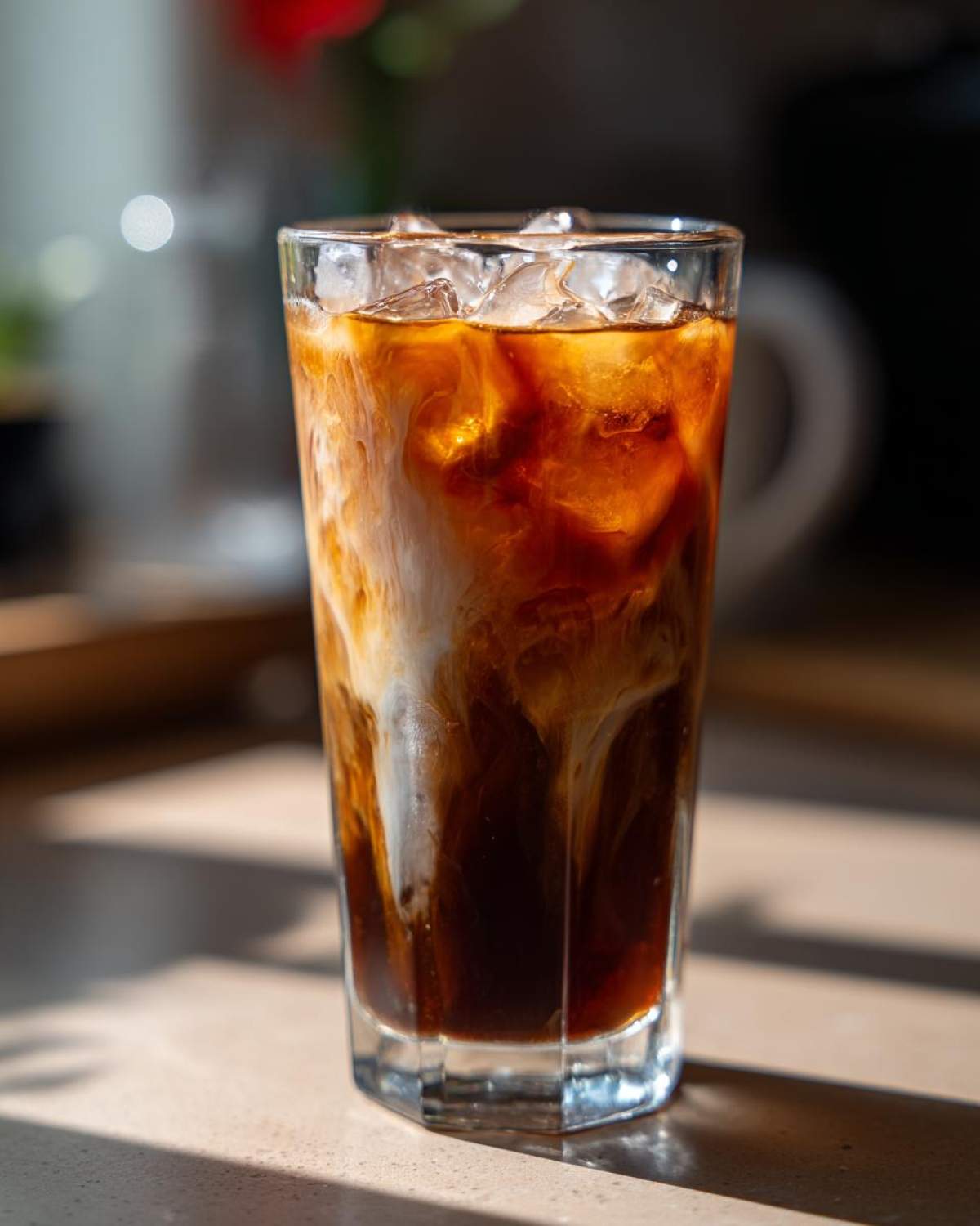 A tall glass filled with Vietnamese Iced Coffee, featuring dark coffee and creamy swirls over ice.