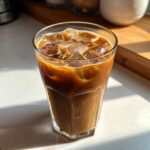 A tall glass filled with Vietnamese Iced Coffee and ice cubes, showing the rich brown color and creamy texture.