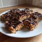 Close-up of several homemade protein bars, made with oats and drizzled generously with dark chocolate.