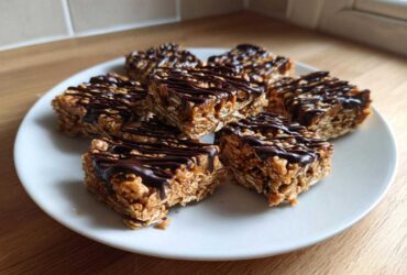 Close-up of several homemade protein bars, made with oats and drizzled generously with dark chocolate.