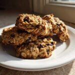 A stack of homemade oatmeal breakfast cookie fuel on a white plate, catching warm morning sunlight.
