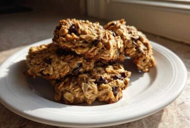 A stack of homemade oatmeal breakfast cookie fuel on a white plate, catching warm morning sunlight.
