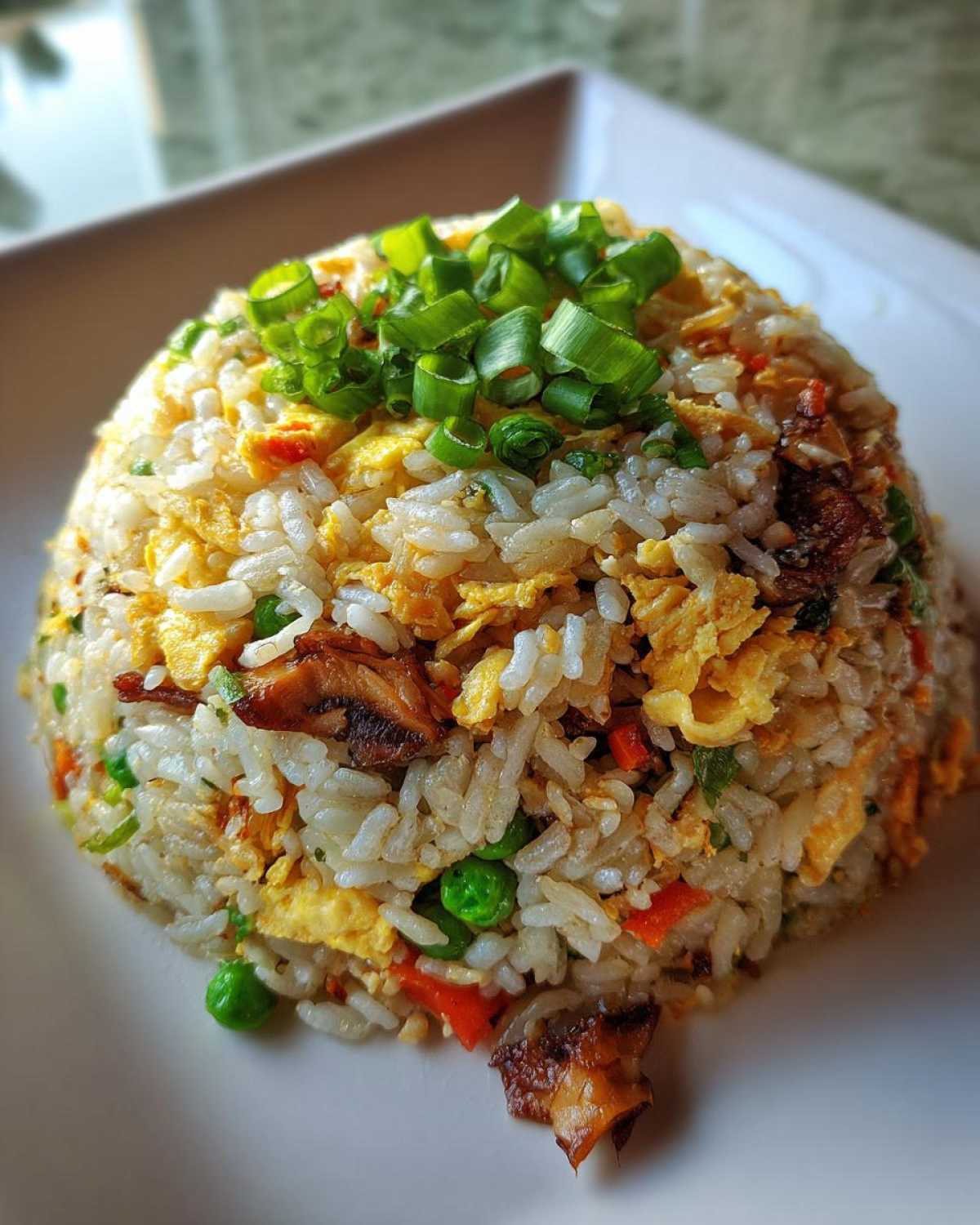 A perfectly molded mound of delicious chicken fried rice topped with fresh green onions.