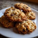 A close-up stack of freshly baked, golden brown oatmeal cookie treats with visible chocolate chips on a white plate.