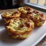 Four golden-brown cottage cheese egg cups starbucks style arranged on a white rectangular plate.