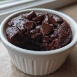A rich, dark chocolate Cottage Cheese Microwave Brownie topped with melted chocolate chips in a white ramekin.