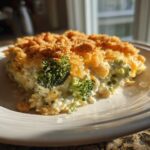 A close-up serving of creamy broccoli casserole topped with golden brown crumbs and melted cheese.