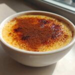 A close-up of creamy rice pudding topped with caramelized sugar and a dusting of cocoa powder.