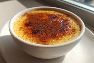 A close-up of creamy rice pudding topped with caramelized sugar and a dusting of cocoa powder.
