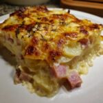 A close-up of a rich, creamy slice of scalloped potatoes and ham with a golden, bubbly cheese topping.