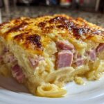 A close-up of a thick, creamy slice of scalloped potatoes and ham with a golden-brown, cheesy top.