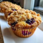 Close-up of a freshly baked blueberry muffin with a thick, sugary crumb topping.