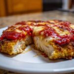 Close-up of a thick, juicy slice of Easy Chicken Parmesan showing melted mozzarella and rich tomato sauce.