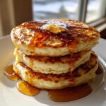 Close-up of a tall stack of fluffy buttermilk pancakes dripping with melted butter and golden syrup.