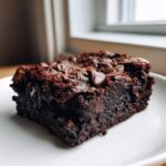 Close-up of a fudgy, dark chocolate sweet potato brownies slice topped with a melted chocolate chip.
