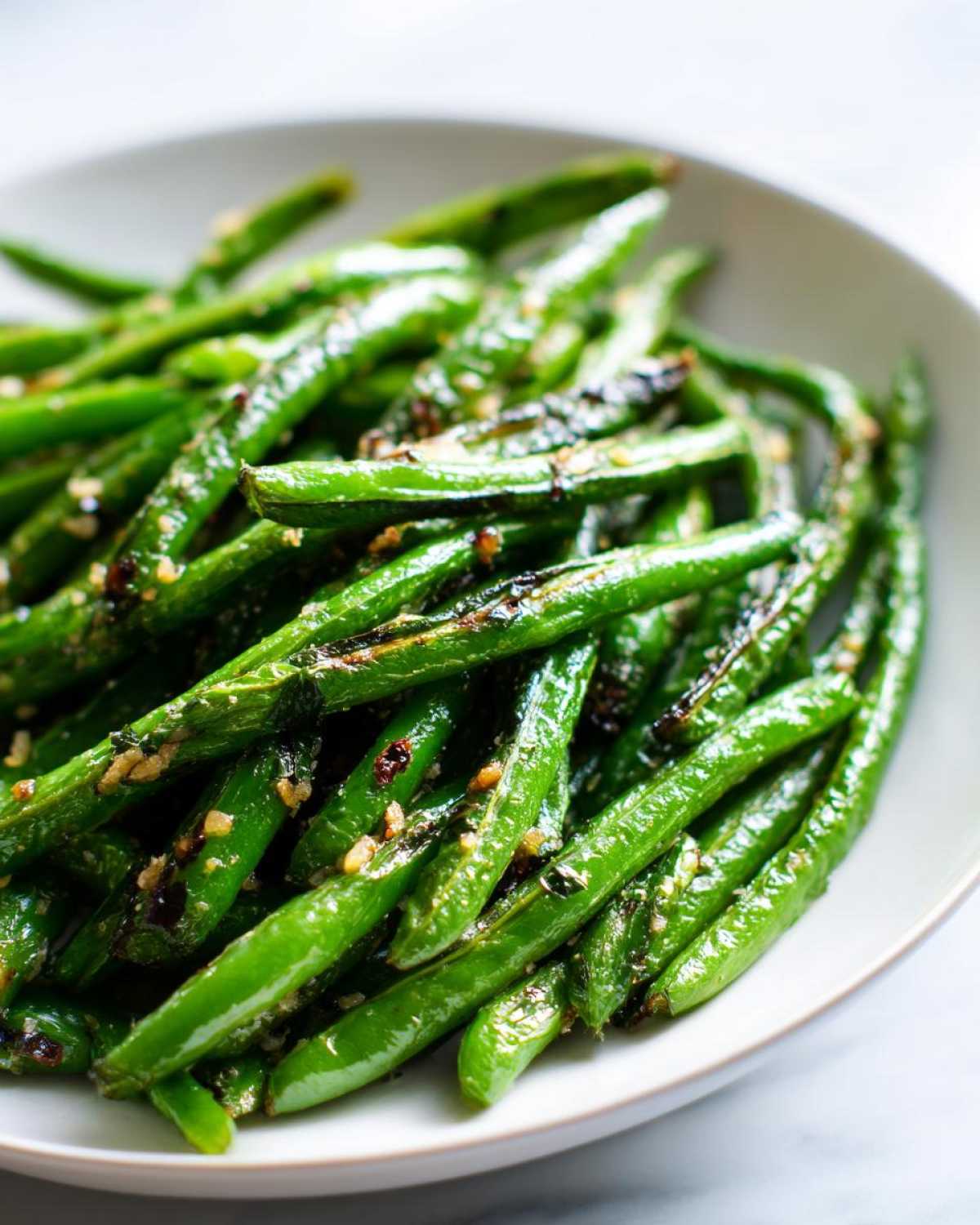 Close-up of bright green beans tossed with garlic and parmesan, ready to serve.
