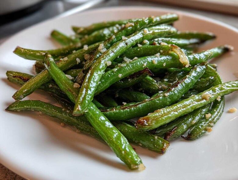 Close-up of bright green beans tossed with minced garlic and Parmesan cheese, ready to eat.