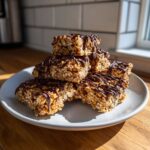 A stack of homemade protein bars made with oats and drizzled generously with dark chocolate.