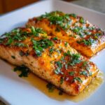 Two perfectly cooked honey garlic salmon fillets glistening with glaze and topped with fresh chopped parsley.