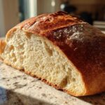 A freshly baked loaf of Italian bread, sliced in half to show the airy interior and golden crust.