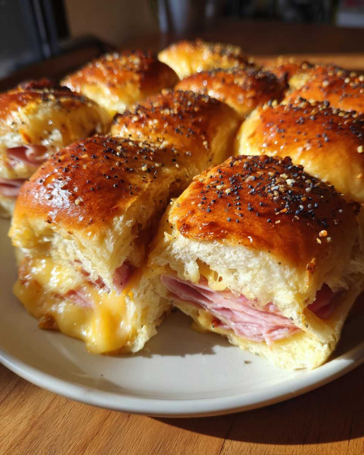 Close-up of freshly baked Ham and Cheese Sliders with gooey melted cheese, topped with poppy seeds.