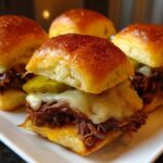 Four delicious Mississippi pot roast sliders stacked with shredded beef, melted cheese, and pickles on brioche buns.