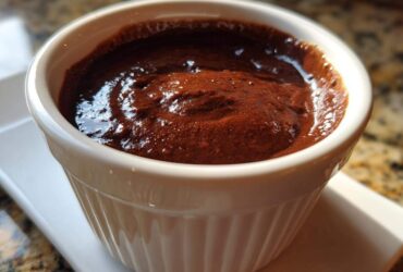 Close-up of rich, dark homemade chocolate pudding served in a white, fluted ramekin.