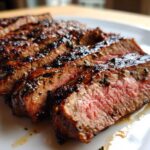 Close-up of sliced steak showing a medium-rare interior, coated in a dark, flavorful carne asada marinade.