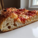 Cross-section view showing the airy crumb structure of a slice of pizza made with sourdough discard pizza dough.