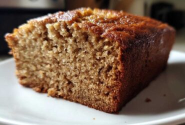 Close-up of a moist, golden-brown slice of sugar free banana bread on a white plate.