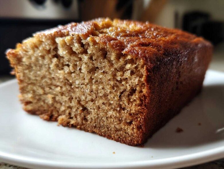 Close-up of a moist, golden-brown slice of sugar free banana bread on a white plate.