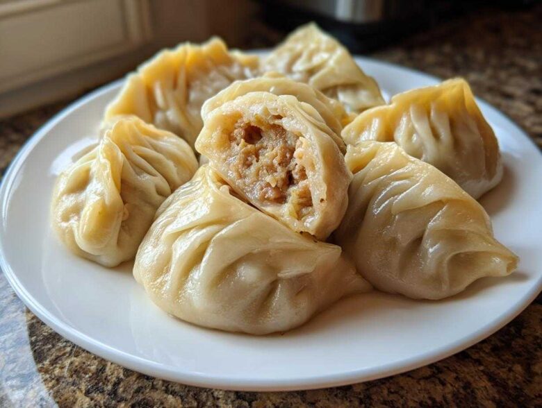 A plate of freshly steamed Traditional Chinese Dumplings, one cut open to show the savory meat filling.