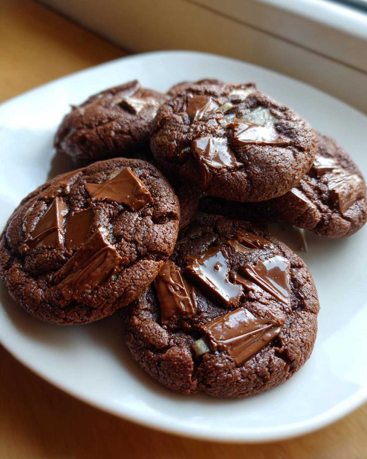 Close-up of several rich, dark chocolate Andes Mint Cookies topped with melted chocolate chunks.