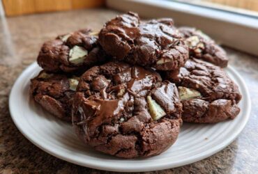 A stack of rich, fudgy Andes Mint Cookies with melted chocolate drizzle and visible mint chips.