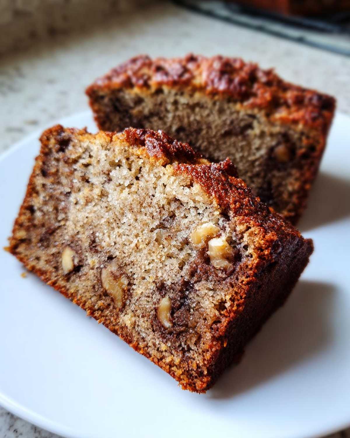 Two moist slices of banana bread, featuring walnuts and a dark, caramelized crust, ready to eat.