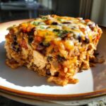 A delicious, cheesy slice of chicken and rice burrito bake topped with melted cheddar and fresh cilantro.
