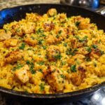 Close-up of chicken scampi with garlic parmesan rice served in a black skillet, garnished with parsley.